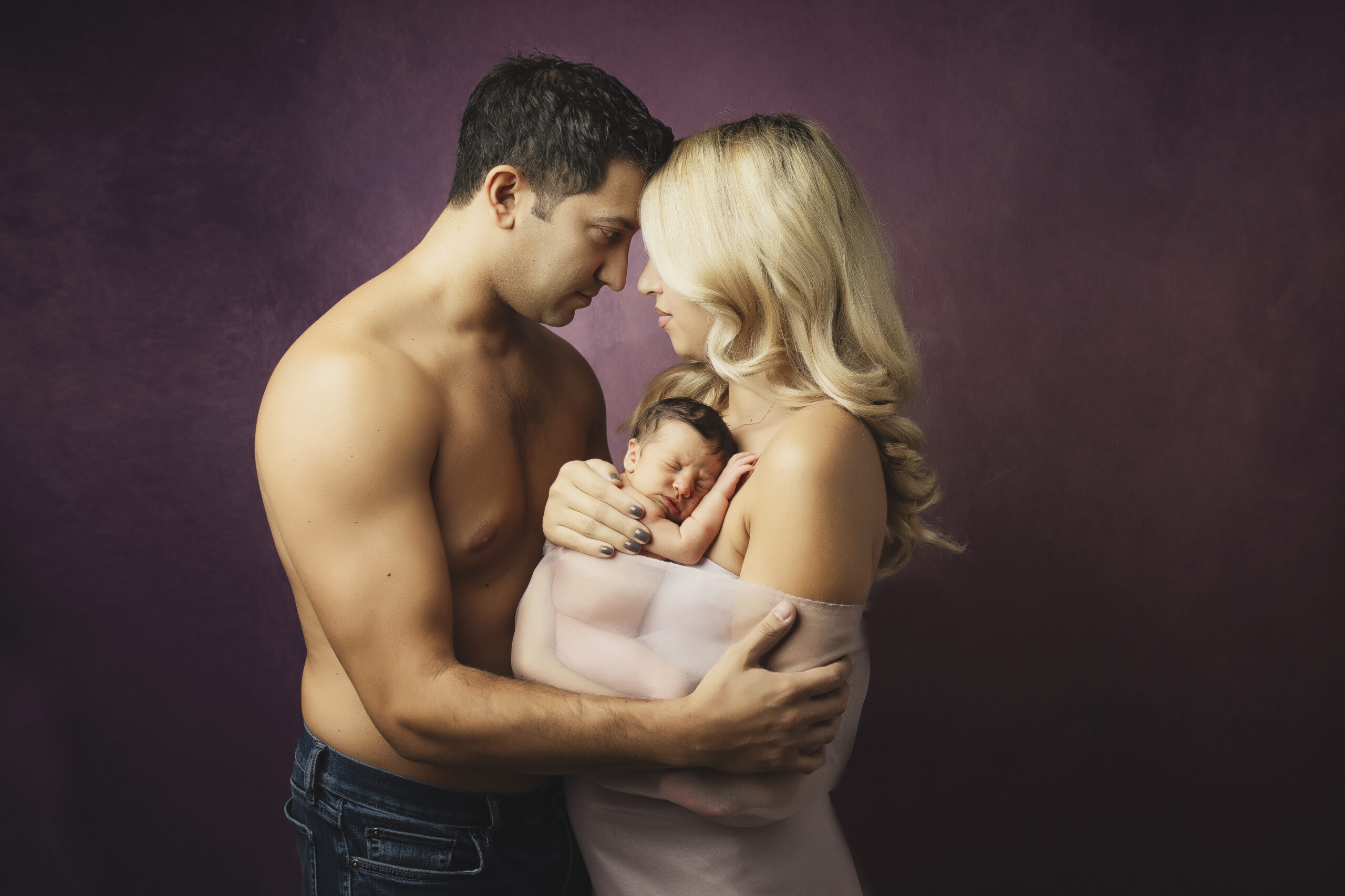 Fine art newborn and parents photo against purple background in Belton TX