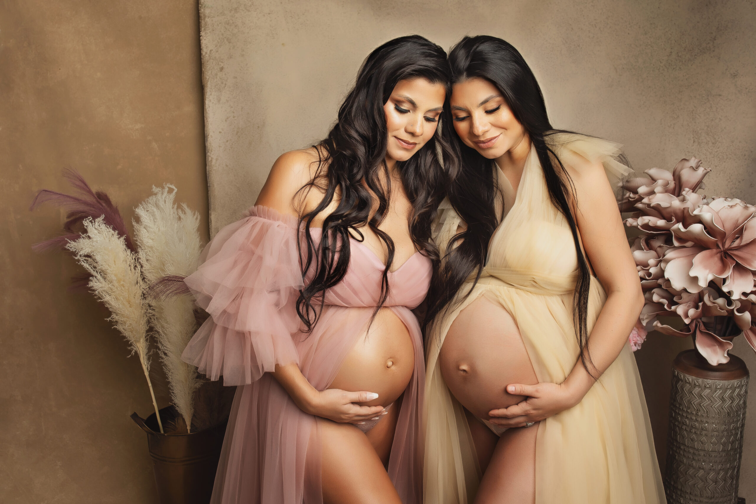 Twin sisters photographed together for their pregnancies wearing pink and beige in ATX